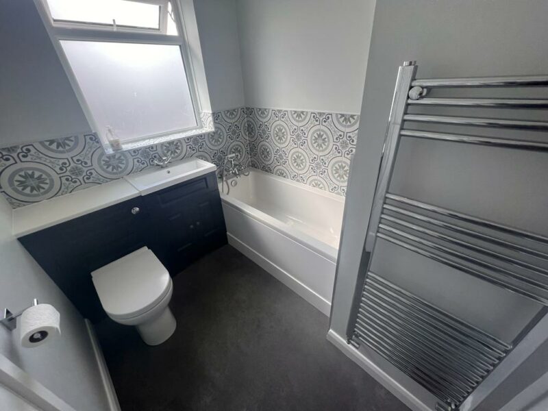 Our services include bathroom fitting like this new bathroom with white toilet, bath and new shower unit